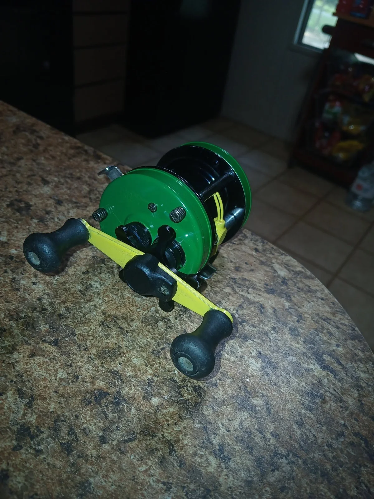 A custom fishing reel with green side plates and yellow handle details, in a photo supplied by BDRX Customs.