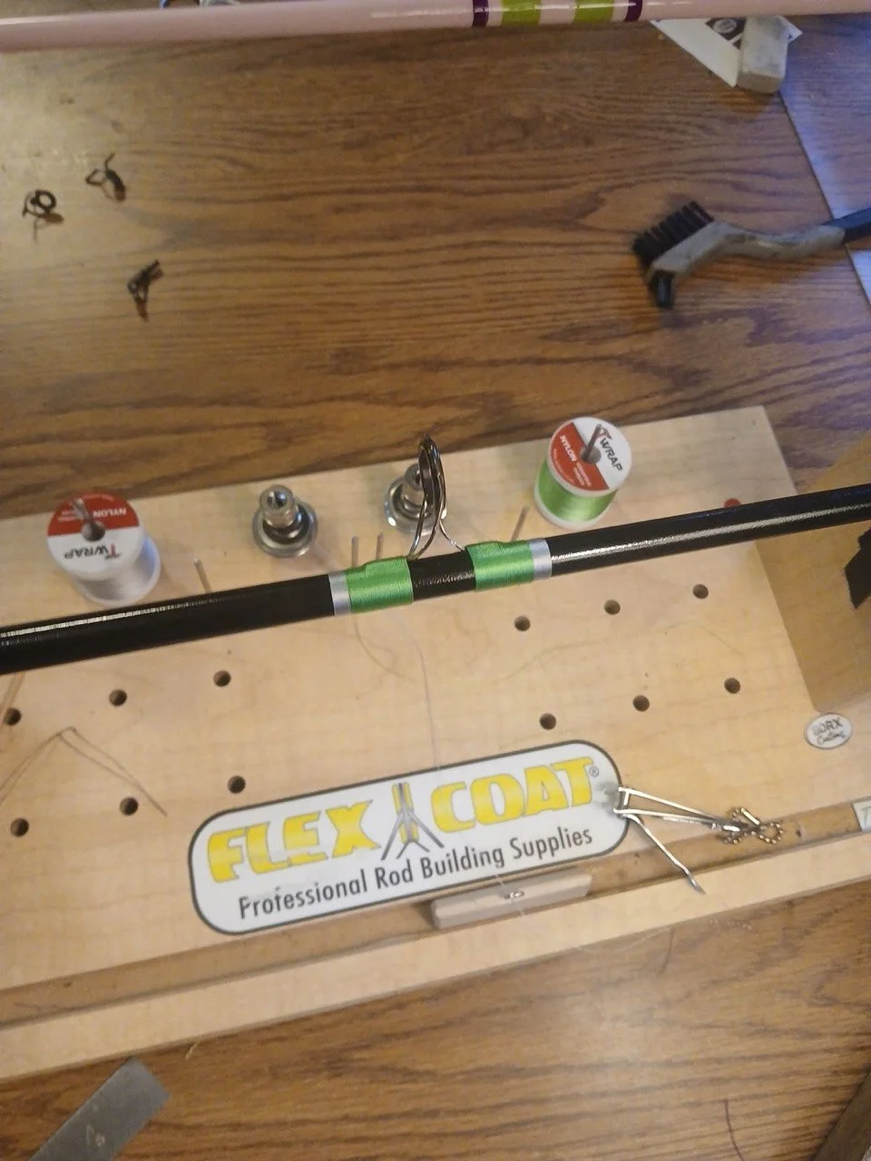 A BDRX Customs fishing rod with green thread wraps and a guide on the rod-building workbench.
